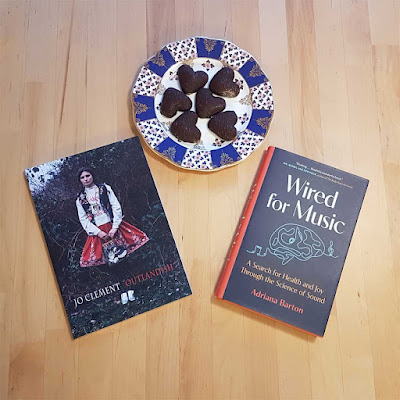 Two books, Outlandish and Wired for Music, on a table with a plate of cookies