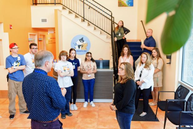 Group of adults and teens having a discussion in the foyer of a building.